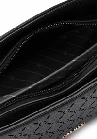 Bolso de cuero negro con diseño floral troquelado, compartimentos dobles con cremallera y forro de tela suave con un sutil patrón a rayas.