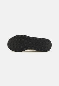 Sola de borracha preta com padrão de piso hexagonal; bordas lisas; marcada com o logótipo "V". Cores e materiais do cabedal não visíveis.