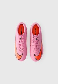 Roosa Nike Mercurial jalgpallijalanõud mustade aktsentidega, oranž swoosh, tekstureeritud pealt, ja lame pael. Kujundatud kiirusel mänguplatsil.