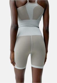 Grijze sporttanktop en bijpassende fietsbroek met gestructureerde ribbel, met een aangesloten ontwerp en contrasterende taillebandaccenten.