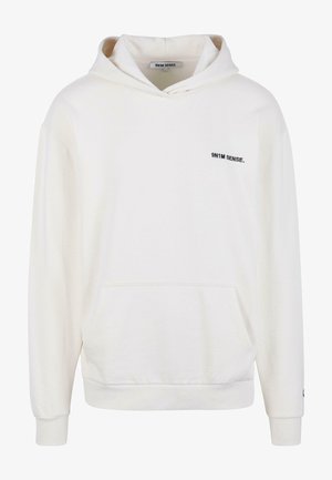 Balts kapuci džemperis ar kangaroo kabatu, ar aukliņu kapuci un mazu melnu logo "9N1M SENSE." kreisajā krūtī. Mīksta auduma tekstūra.