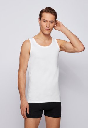 Débardeur blanc en coton, avec un décolleté ras du cou et de larges bretelles, associé à un short boxeur noir. Texture lisse.