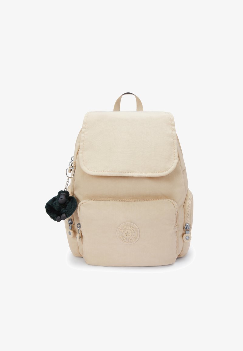 Zaino in tessuto beige con chiusura a patta, due tasche frontali con zip e un logo circolare; presenta un portachiavi a forma di scimmia pelosa verde.