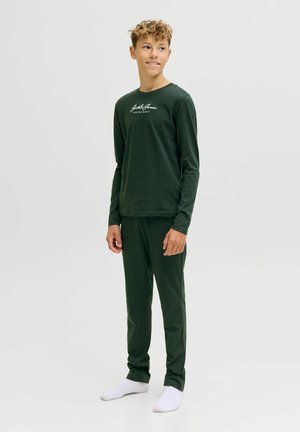 Donkergroen langemouwen shirt en bijpassende broek van zacht materiaal, met een geschreven logo op de borst. Witte sokken.
