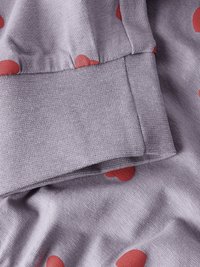 Μωβ ύφασμα με απαλό υφή που διαθέτει κόκκινα σχέδια καρδιάς. Το ένδυμα έχει ριμπ μανσέτα, παρουσιάζοντας ένα χαλαρό σχέδιο.