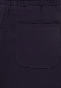 Pantaloni della tuta in cotone blu navy con tasca posteriore, vita elastica e tessuto liscio. Dettagli di cucitura visibili intorno ai bordi delle tasche.