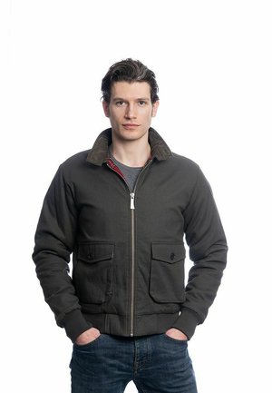 Veste bomber vert foncé en mélange de coton, avec un col en velours côtelé, une fermeture éclair à l'avant et deux poches poitrine à bouton.