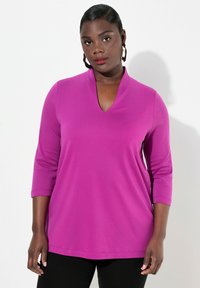 Magenta Langarmshirt mit V-Ausschnitt und Dreiviertelärmeln. Weicher Stoff mit glatter Textur, in lockerer, lässiger Passform.