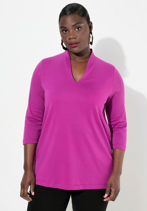 Top magenta a maniche lunghe con scollatura a V e maniche a tre quarti. Tessuto morbido con una trama liscia, caratterizzato da una vestibilità ampia e rilassata.