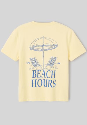 T-shirt jaune avec illustration bleue d’un parasol de plage, deux chaises longues indiquant 14h et 16h, et le texte « BEACH HOURS » en dessous.