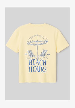 T-shirt jaune avec illustration bleue d’un parasol de plage, deux chaises longues indiquant 14h et 16h, et le texte « BEACH HOURS » en dessous.