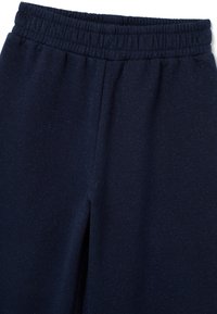 Navyblaue Jogginghose mit elastischem Bund; weicher, strukturierter Stoff mit dezenten Sprenkeln, taillierter Beinführung und ohne sichtbare Taschen.