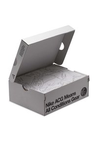 Άσπρο κουτί παπουτσιών Nike ACG ανοιχτό, που δείχνει ένα λευκό εσωτερικό κουτί με σχέδιο τοπογραφικού χάρτη, το κείμενο λέει "Nike ACG Means All Conditions Gear."