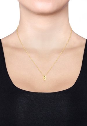 Goldene Halskette mit einem kleinen, glänzenden Anhänger in Form des Buchstabens "S". Die Kette hat ein gedrehtes Design und liegt auf nackter Haut.