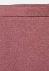 Pogled od blizu na nabrano mauve pleteno blago, ki prikazuje fino tkano teksturo in horizontalni šiv blizu zgornjega roba.