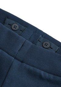 Tummansininen vyötärönauha ribbineuloksella, jossa on kaksi mustaa nappia ja lenkkiaukot. Kangas on sileä, mikä viittaa pehmeään materiaaliin.