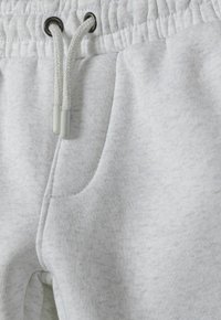 Light gray sweatpants featuring a textured fabric, elastic waistband with drawstrings, and side pocket detail.