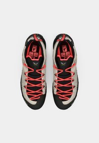 Sportliche Schuhe mit einem beigen Mesh-Obermaterial, schwarzen Akzenten und leuchtend orangenen Schnürsenkeln. Verfügt über eine strukturierte Sohle und Innenpolsterung mit Etikettendetails.