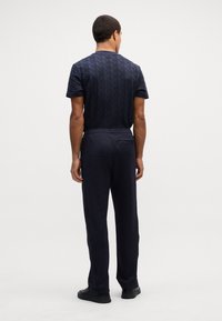 T-Shirt navy a maniche corte con motivo geometrico testurizzato e pantaloni navy abbinati con tasca sul retro. Entrambi sono realizzati in tessuto morbido.