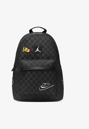 Czarny plecak z wzorzystym designem, wyraźnymi naszywkami z logo oraz zamykanymi kieszeniami. Zawiera teksturowaną powierzchnię i regulowane paski.
