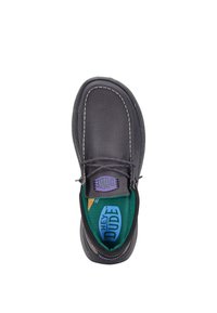 Zapato de lona gris sin cordones con costuras en contraste, plantilla verde y detalle de logo morado. Cuenta con una puntera redondeada y suela flexible.