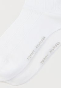 Άσπρες βαμβακερές αθλητικές κάλτσες με ριγωτό σχέδιο και το λογότυπο "TOMMY HILFIGER" τυπωμένο στον αστράγαλο σε γκρι χρώμα. Ομαλή υφή, κανονικό μήκος.