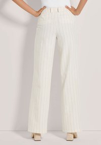 Witte gestreepte wijde broek met een ceintuur in de taille, voorzien van voorzakken en een gladde textuur, gecombineerd met beige blokhak schoenen.