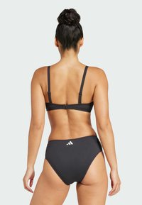 Čierny bikini s nastaviteľnými ramienkami, jednoduchý dizajn a detail loga na zadnej strane nohavičiek, s hladkou textúrou a strihom.