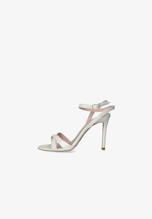 Sandalo stiletto bianco con design a cinturino incrociato, cinturino alla caviglia regolabile e tacco sottile. Finitura in pelle liscia con una leggera fodera rosa.