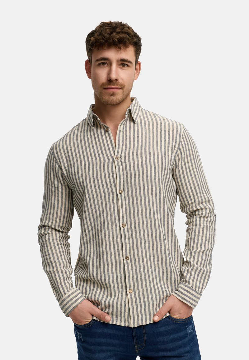 Camicia a righe con bottoni in crema e blu navy. Presenta maniche lunghe, colletto e bottoni in legno. Il materiale ha un aspetto texturizzato e tessuto.