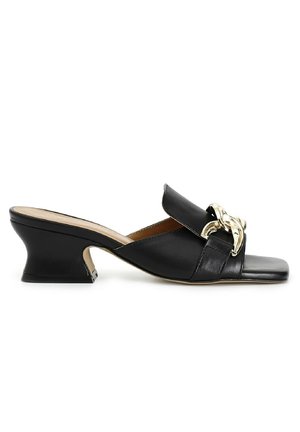 Sandales noires en cuir avec une large bride ornée d'une chaîne en or, un bout carré et un talon sculpté pour plus de hauteur.
