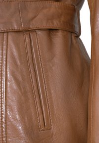 Braune Lederjacke mit glatter Textur, tailliertem Schnitt und seitlichen Schlitztaschen mit sichtbaren Steppnähten.