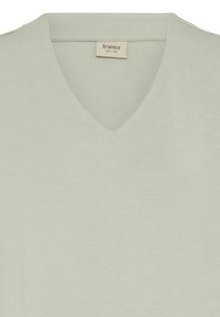 Jasnozielony t-shirt z krótkim rękawem i dekoltem w serek, wykonany z miękkiej tkaniny o gładkiej fakturze. Metka z napisem "fransa" w swobodnej czcionce.