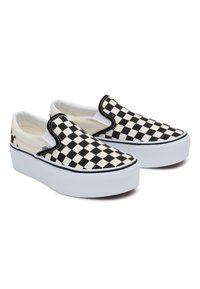 Zwart-witte geruite instapschoenen met een platte witte zool en contrasterende zwarte bies, voorzien van een bovenkant van canvas en elastische zijaccenten.