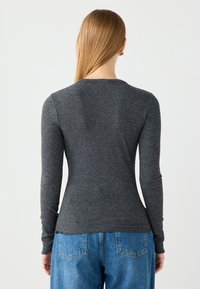 Grijze langärmige top van ribgebreid katoen, met een ronde hals en een aansluitende silhoette, gecombineerd met losse blauwe jeans.