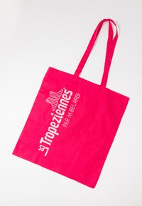 Bolsa de tela rosa brillante con asas largas, logo blanco "La Tropezienne PAR M.BELARBI" y diseño de estrella a rayas en un lateral.