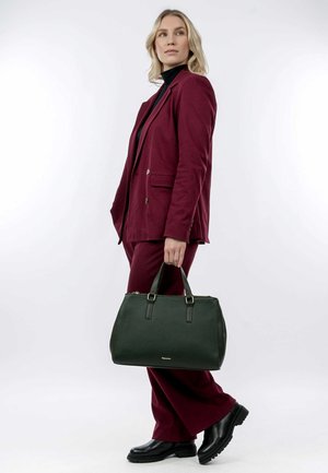 Borsa a tracolla in pelle verde scuro con superficie texturizzata e accessori in argento, dotata di manici superiori doppi e chiusura con zip, tenuta da una persona.