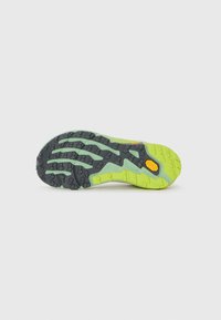 Sole of a green and black Vibram running shoe with deep treads and an orange Vibram logo on a white background.