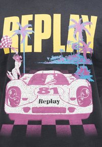 Αυτοκίνητο αγώνων με τον αριθμό 81 σε γραμμή τερματισμού με σκακιέρα, φοίνικες και μεγάλο κίτρινο κείμενο «ΕΠΑΝΑΛΗΨΗ» στο παρασκήνιο.