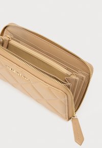 Brązowy skórzany portfel z pikowanym wzorem, złotym zamkiem błyskawicznym, wieloma przegródkami oraz złotym logo marki na zewnątrz.