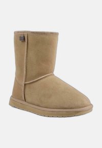 Botín de ante en color marrón con punta redondeada, detalles de costura y suela de goma. Presenta una pequeña etiqueta con el logo cerca del borde superior.