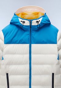 Blå och krämfärgad vadderad jacka med huva, med dragkedja fram, två sidofickor och en kontrasterande gul innerfoder.