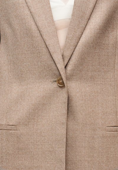 Blazer marron en tissu texturé avec une fermeture à un seul bouton, des revers en encoche et deux poches avant. L'intérieur est de couleur claire.