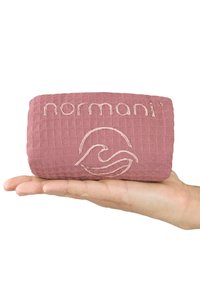 Rechteckiges pinkes Kissen mit strukturiertem Gittermuster, das mit dem gestickten "normani"-Logo und einem Wellenmuster versehen ist. In einer Hand gehalten zur Größenangabe.