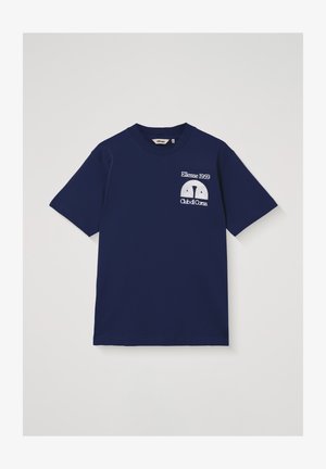 Tamsiai mėlynas trumpomis rankovėmis marškinėlis su baltu užrašu „Ellesse 1959 Club di Corsa“ ir puslankiniu logotipu ant kairės krūtinės.