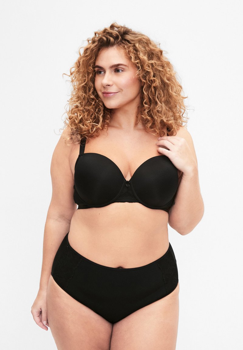 Soutien-gorge noir rembourré avec armatures, texture lisse, bretelles ajustables et un fermoir décoratif au centre. Associé à un slip noir taille haute avec des accents en dentelle.