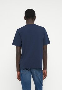 Μπλε ναυτικό κοντομάνικο T-shirt από μαλακό, υφασματικό ύφασμα με υφή. Διαθέτει κλασικό στρογγυλό λαιμό και άνετη εφαρμογή. Απλό σχέδιο, χωρίς ορατά μοτίβα.