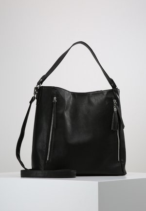 Zwarte leren schoudertas met twee verticale voorvakken met rits, een afneembare crossbodyriem en een decoratieve kwast aan een van de ritssluitingen.