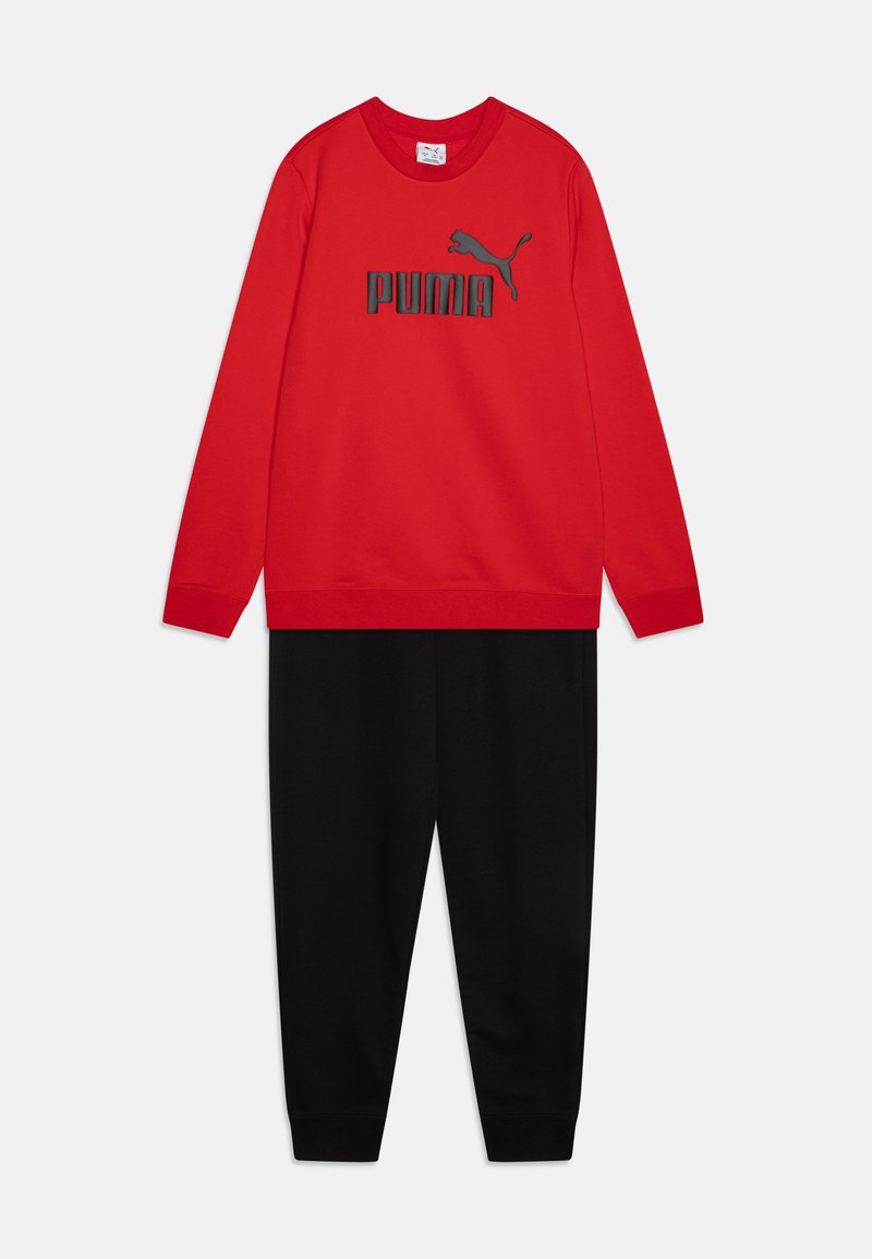Sarkans džemperis ar melnu "PUMA" logo un atbilstošām melnām sporta biksēm. Materiāls šķiet mīksts; tam ir garas piedurknes un elastīgas aproces.