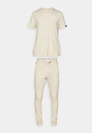 Beige színű pamut rövid ujjú póló és melegítőnadrág szett. A póló kerek nyakú; a melegítőnadrág rugalmas derékrésszel és passzos szegéllyel rendelkezik. Mindkét darabon logo található.